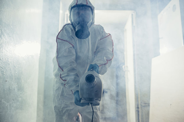 Image of operator in Hazmat suit in the process of fogging activity